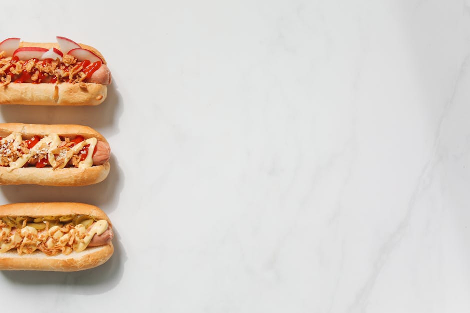 Three gourmet hot dogs with various toppings on a marble background. Perfect for food photography enthusiasts