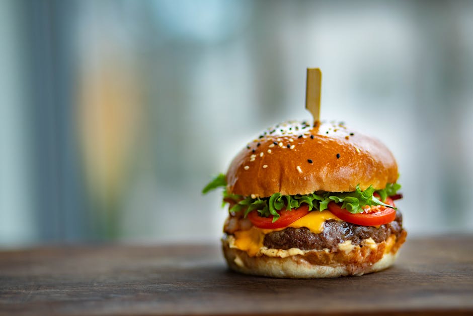 Mouthwatering cheeseburger with fresh tomatoes and lettuce on a wooden surface